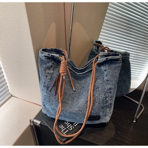 Détail du sac cabas en jean délavé avec anses en corde tressée et patch logo en cuir