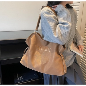 Detail of khaki tote bag featuring daisy embroidery and adjustable drawstring side