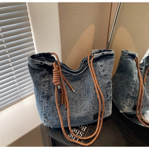 Gros plan du sac fourre-tout en denim délavé bleu avec poignée en corde tressée orange