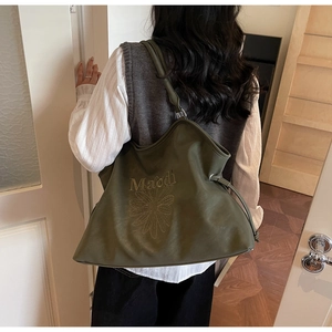 Detail of olive green leather tote bag with daisy embroidery and drawstring design