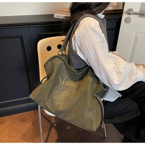Detail of olive green tote bag featuring delicate daisy embroidery and soft leather texture