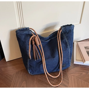 Détail du sac cabas en jean bleu avec anses en corde marron et accents de franges
