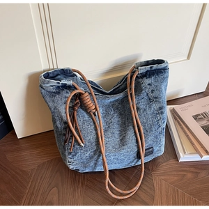 Détail d'un sac cabas en denim vintage avec poignée en corde tressée et texture denim