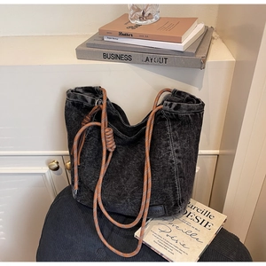 Détail du sac cabas en denim noir délavé avec anse en corde tressée et empiècement cuir