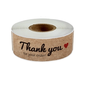 Macro view of kraft paper 'Thank you for your order' adhesive labels on a roll