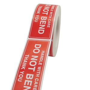 Roll of red Fragile Handle With Care rectangular shipping labels with white bold text
