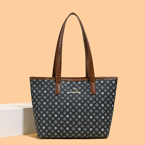 Detail of printed tote bag featuring metallic kangaroo logo and brown leather handles