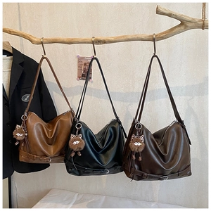 Three vintage tote bags in caramel, black, and coffee hung on wooden branches