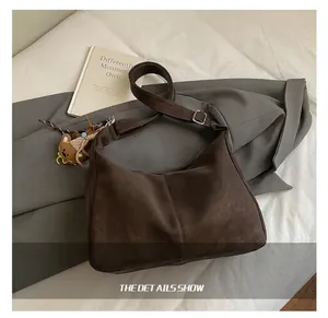 Dettaglio borsa hobo marrone scuro con tracolla regolabile e ciondolo a forma di orso
