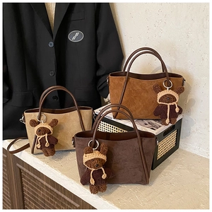 Nahaufnahme der matten Ledertaschen in Khaki und Braun mit kleinen Bärenanhängern
