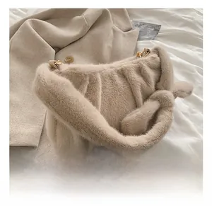 Détail du sac sous le bras en peluche beige avec poignée nouée et chaîne en métal doré