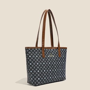 Detail of grey tote bag with monogram pattern and golden kangaroo metal logo plaque