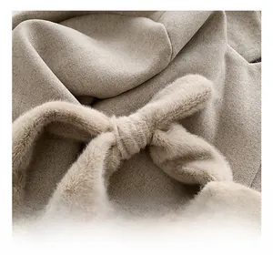 Gros plan détaillé sur la poignée en peluche nouée et le tissu en tweed beige du sac à main