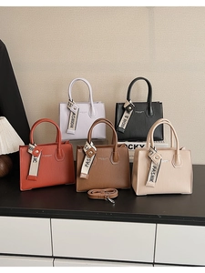 Close-up of elegant pleated handbags in purple, black, red, brown and beige with ribbons