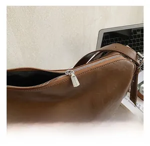 Detail view of the silver metal zipper and hardware on a brown leather tote bag