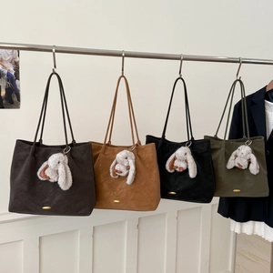 Row of four colorful faux suede tote bags with cute bunny pendants hanging on a rack