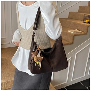 Dettaglio della borsa tote in pelle marrone scuro con ciondolo a forma di orsetto