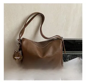 Detailed view of brown lychee texture tote bag with a leopard bow plush charm on a desk