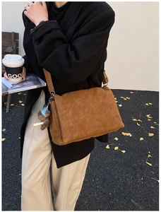 Brown quilted crossbody bag with plush bear charm worn by a model in autumn street style