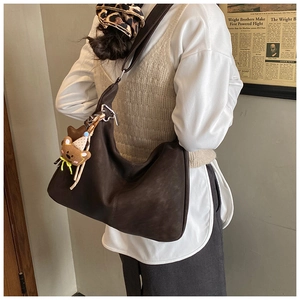 Dettaglio borsa hobo marrone scuro con ciondolo a forma di orsetto sulla tracolla morbida