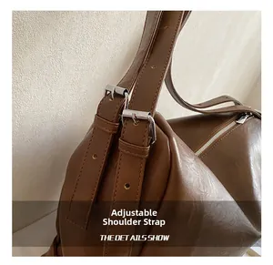 Close-up of the adjustable strap detail and silver buckle on a brown leather tote bag