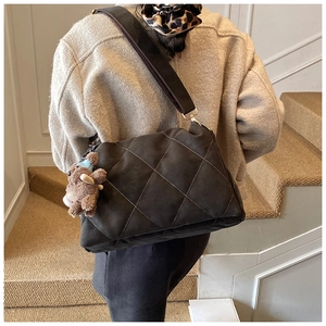 Detail of vintage coffee brown quilted tote bag with a plush bear charm and wide strap