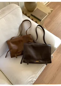 Detailansicht von Leder-Schultertaschen in Karamell und Kaffee auf einem Sofa