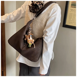 Dettaglio di borsa tote vintage in pelle marrone con ciondolo a forma di orsetto