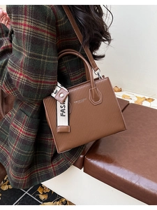 Detail of brown striped texture crossbody bag shown with autumn ginkgo leaves