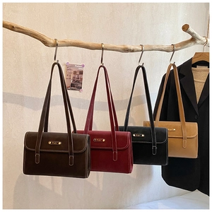 Detail view of four vintage leather shoulder bags with white stitching hanging on a wood branch