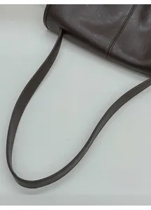 Detail der dunkelbraunen Ledertasche mit breitem Schultergurt und feiner Nähtechnik
