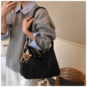 Dettaglio di una borsa tote nera capiente in nylon con un grazioso ciondolo a orsetto
