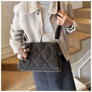 Detail of dark grey quilted crossbody bag with adjustable strap and plush bear charm