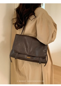 Detailansicht der tiefbraunen Retro-Leder-Achseltasche getragen zu einem beigen Trenchcoat