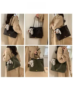 Detail of corduroy tote bags in brown and green with golden logo and plush bunny charm