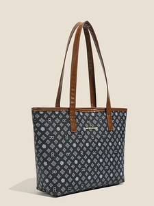 Black leather tote bag with white monogram print and brown handles in a side-view studio shot