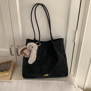 Close-up of black matte tote bag featuring thin straps and a cute rabbit plush pendant