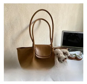 Brown tote bag detail with plush bunny charm and elegant flap closure shown in a lifestyle set