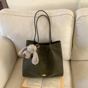 Detail of olive green suede tote bag with golden metal buckle and cute rabbit pendant