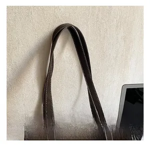 Detail of reinforced handles with contrast white stitching on dark brown leather tote