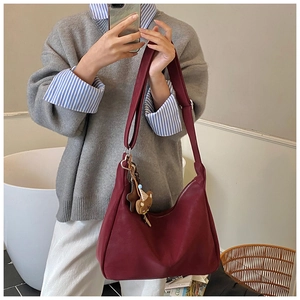 Dettaglio della borsa hobo bordeaux in pelle liscia con un simpatico ciondolo a orso