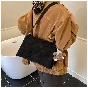 Detail view of black quilted tote bag with soft suede texture and cute brown bear charm