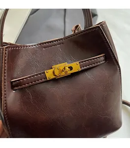 Dettaglio borsa a secchiello marrone scuro con chiusura a rotazione in metallo dorato