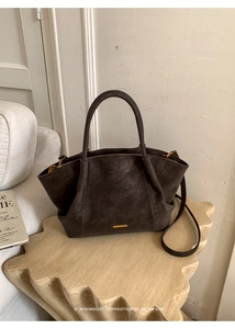 Detailed close-up of retro minimalist bucket bag with fine leather texture and golden metal logo