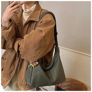 Dettaglio della borsa hobo verde oliva scuro con un simpatico ciondolo orso ricamato