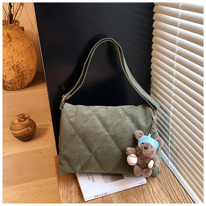 Detail of dark green quilted tote bag in suede finish with cute bear pendant