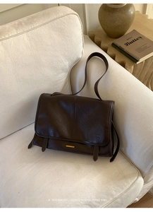 Detailaufnahme einer braunen Retro-Tasche mit Metallschnalle auf weißem Stoffsofa