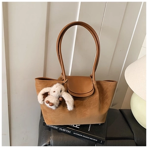 Detail of tan suede tote bag with brown leather flap and cute plush bunny charm