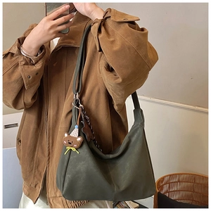 Dettaglio della borsa tote verde scuro con un simpatico ciondolo a forma di orso