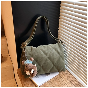 Close-up of dark green quilted tote bag with matte texture and cute bear charm detail